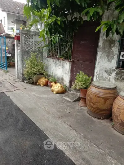 Charming rustic exterior with traditional pottery and lush greenery.