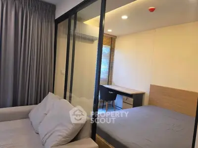 Modern studio apartment with glass partition, cozy bed, and study area.