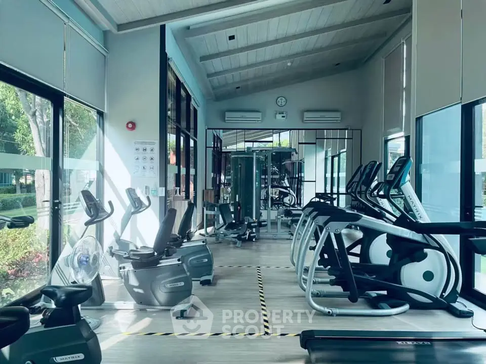 Modern gym with state-of-the-art equipment and large windows offering garden views.