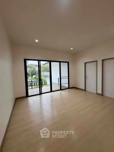 Spacious empty room with large windows and wooden flooring, perfect for customization.