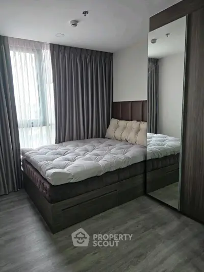 Modern bedroom with plush bedding and mirrored wardrobe in stylish apartment.