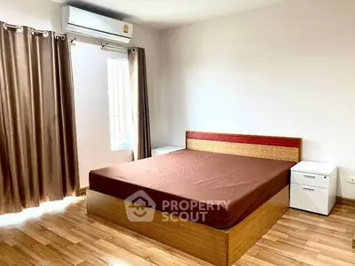 Spacious bedroom with wooden flooring and modern air conditioning unit.