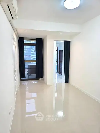 Spacious modern living room with sleek tile flooring and large windows for natural light.