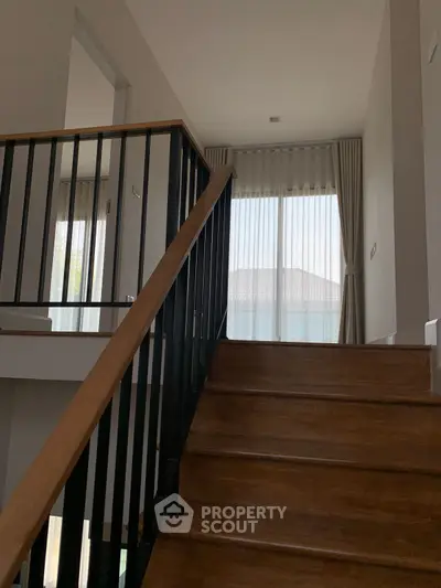 Elegant staircase with wooden steps and modern railing in a bright home interior.
