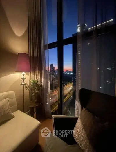 Cozy living room with plush seating and floor-to-ceiling windows offering a breathtaking city skyline view at dusk, perfect for urban living.