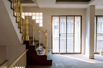 Spacious interior with elegant staircase and large windows offering natural light.