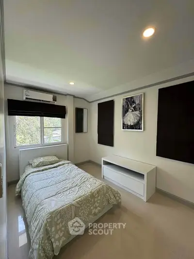 Cozy bedroom with natural light and modern decor, featuring a comfortable bed and stylish artwork.