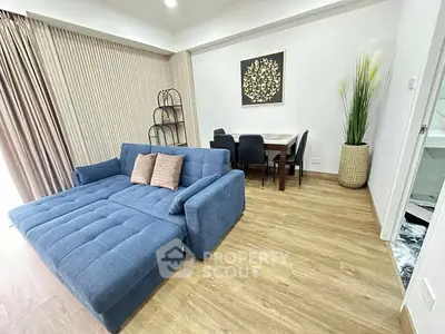 Modern living room with blue sofa and dining area, featuring stylish decor and wooden flooring.