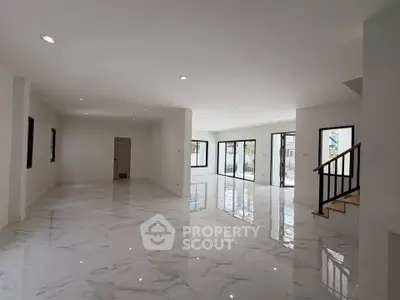 Spacious modern living room with glossy marble floors and large windows for natural light.
