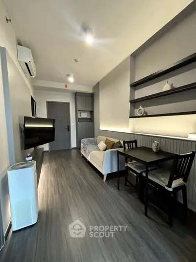 Modern living room with sleek flooring, cozy sofa, and dining area in a stylish apartment.