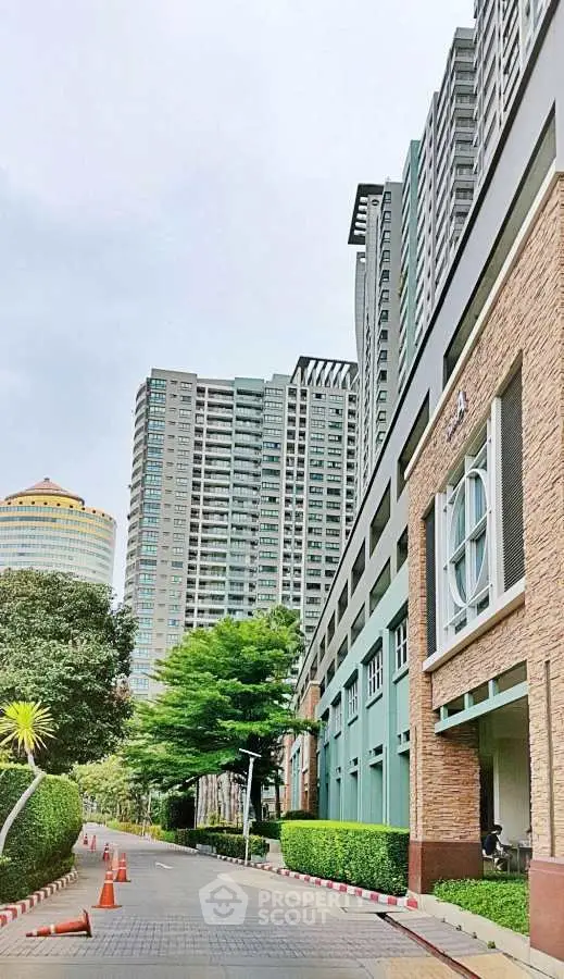 Modern high-rise building exterior with lush greenery and clear sky