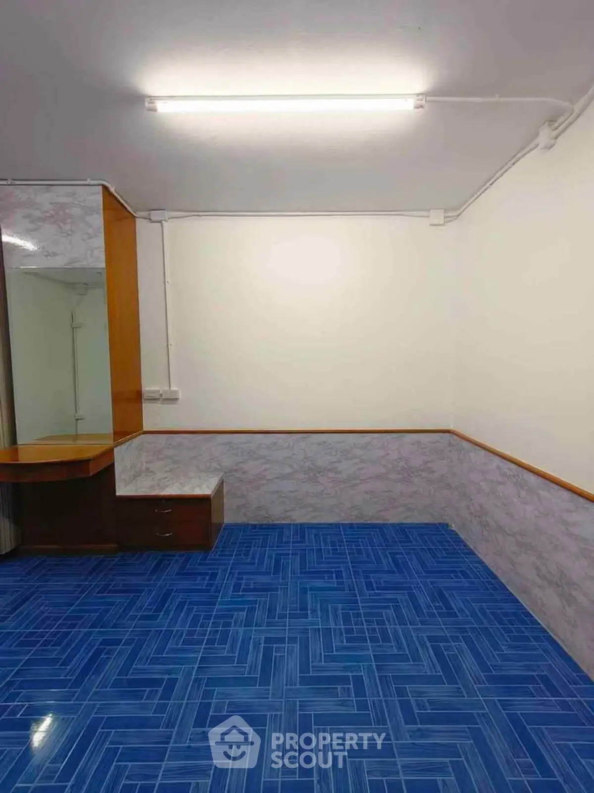 Spacious room with blue tiled flooring and wooden furniture, ideal for versatile use.