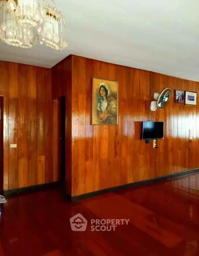 Spacious living room with wooden paneling and elegant chandelier