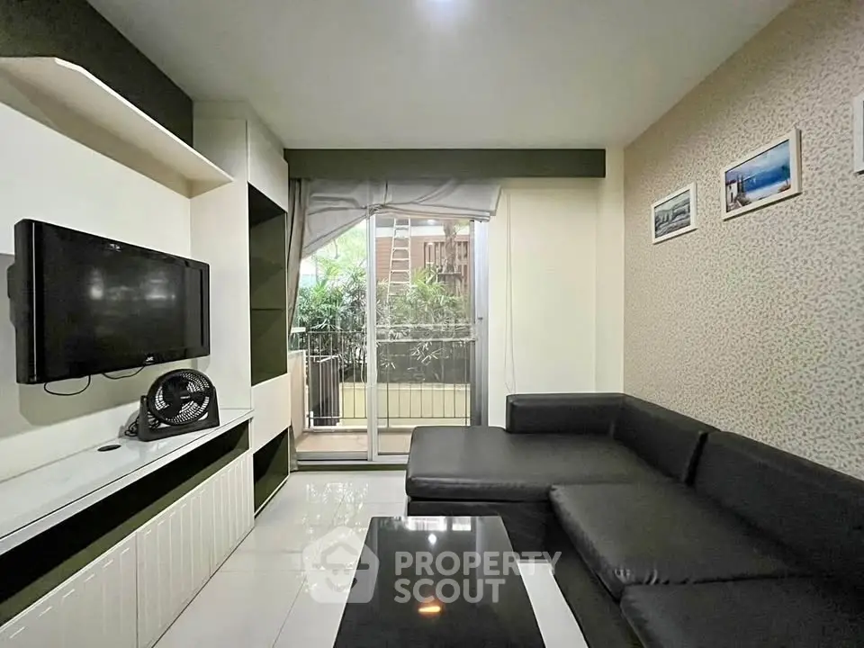 Modern living room with sleek black sofa and balcony view, perfect for urban living.