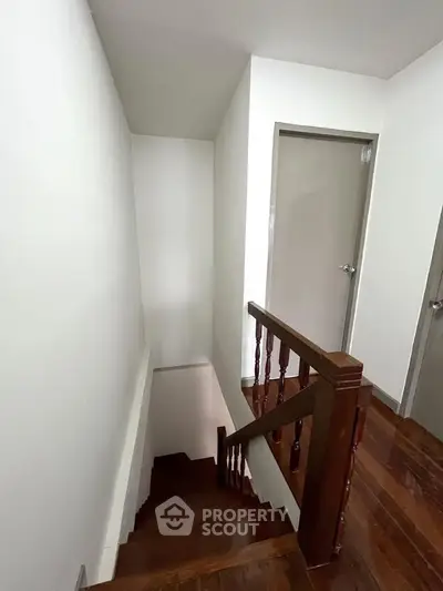 Charming wooden staircase in a modern home with sleek white walls and elegant wooden railings.