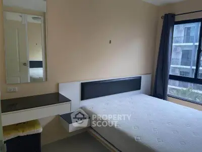 Modern bedroom with large window and built-in vanity in urban apartment