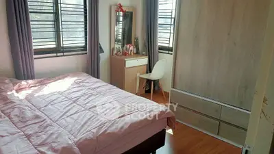 Cozy bedroom with wooden flooring, large window, and modern furniture.