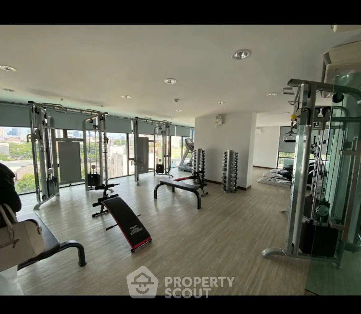 Spacious gym with modern equipment and city view, perfect for fitness enthusiasts.