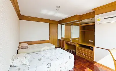 Spacious bedroom with twin beds and built-in wooden storage, perfect for comfortable living.