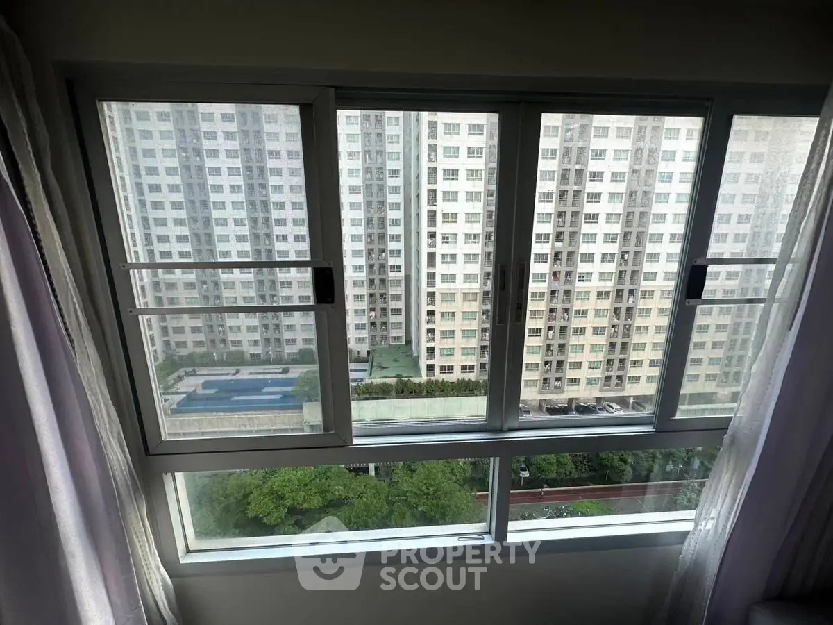 High-rise apartment window view with pool and garden below