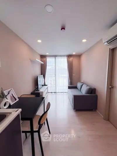 Modern living room with sleek furniture and large window offering natural light and city view.