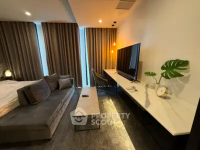 Modern bedroom with stylish decor and large TV, featuring elegant curtains and a sleek marble table.