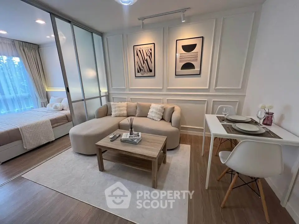 Modern open-plan living room with cozy seating and stylish decor adjacent to a bedroom.