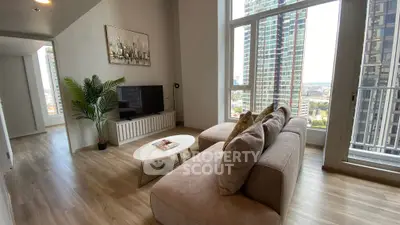 Modern living room with large windows and city view, featuring stylish decor and cozy seating.