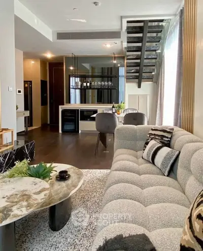 Luxurious modern living room with stylish decor and open kitchen layout, featuring elegant staircase and plush seating.