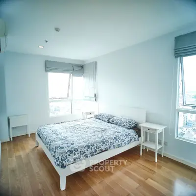 Spacious bedroom with large windows and wooden flooring in modern apartment