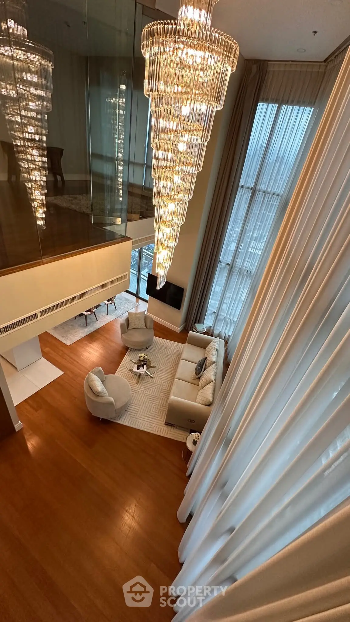 Luxurious high-ceiling living room with elegant chandelier and floor-to-ceiling windows.