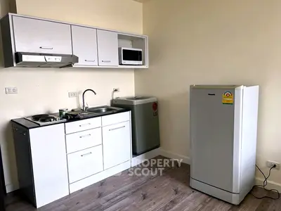 Modern compact kitchen with appliances including fridge, microwave, and washing machine in a cozy apartment.