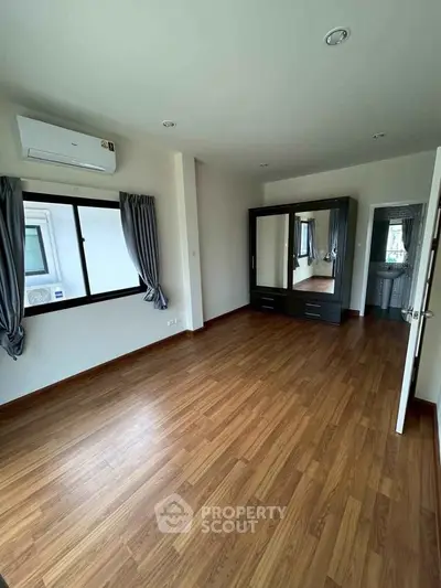 Spacious bedroom with wooden flooring and modern wardrobe