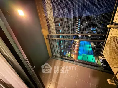 Cozy balcony with night view of illuminated pool and modern building, perfect for relaxation.