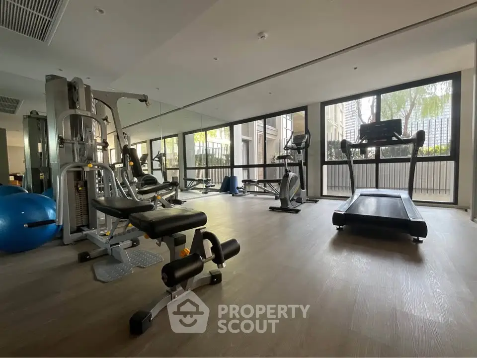 Modern gym with state-of-the-art equipment and large windows in a luxury residential building.