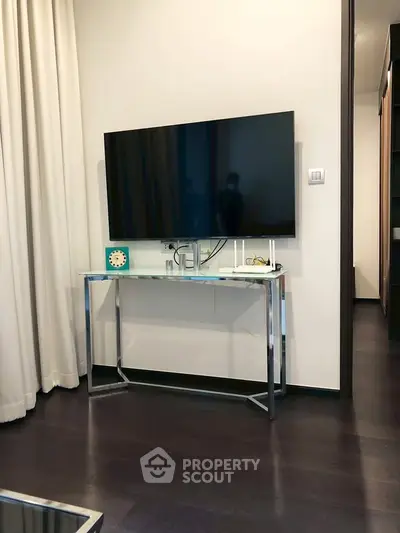 Modern living room with sleek TV setup and elegant dark wood flooring.