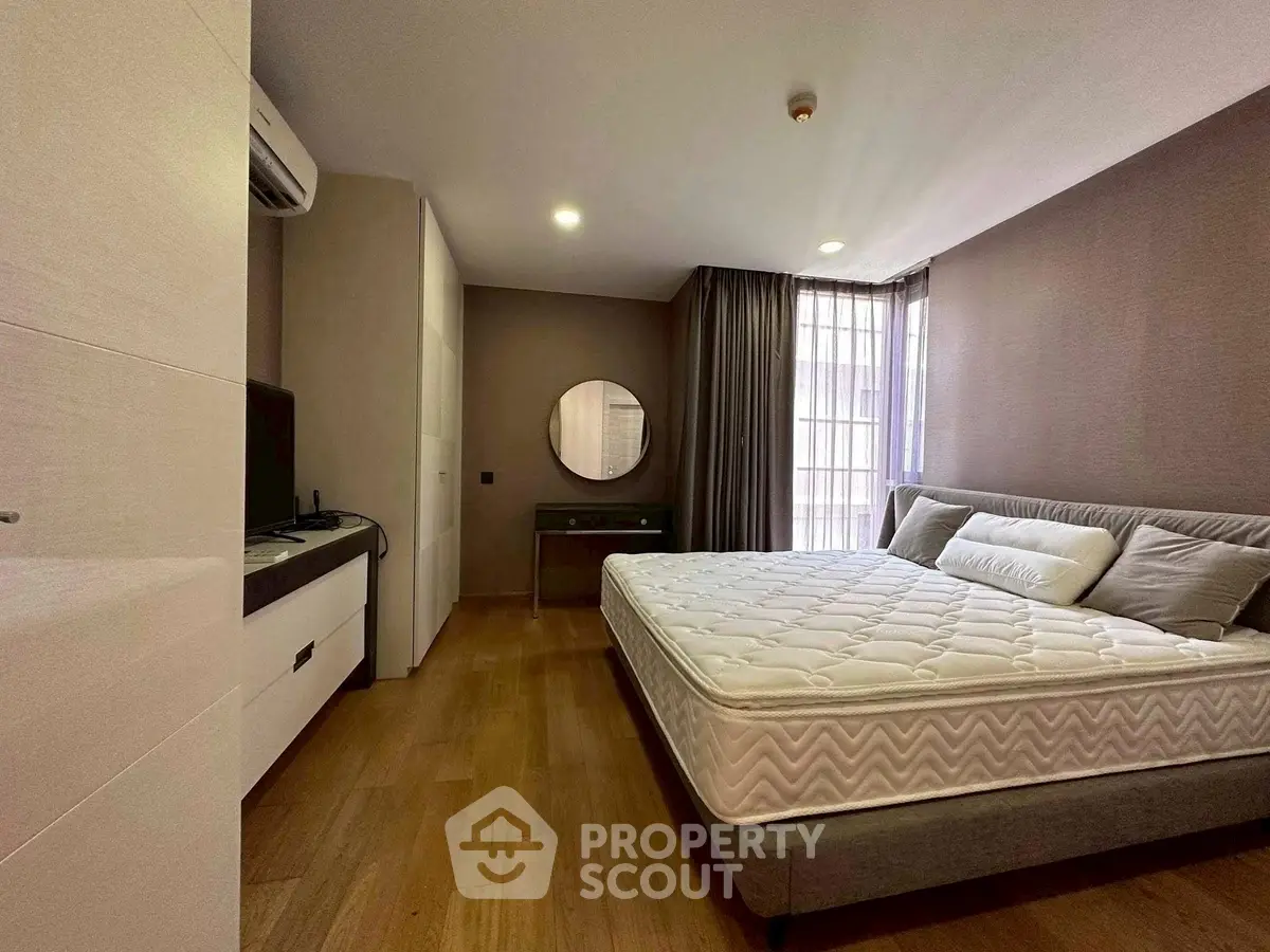 Spacious bedroom with modern decor and large window for natural light.