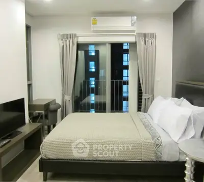 Modern bedroom with balcony view, featuring a cozy bed, TV, and air conditioning for ultimate comfort.