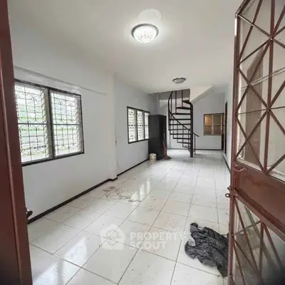 Spacious interior with spiral staircase and large windows in a modern home.