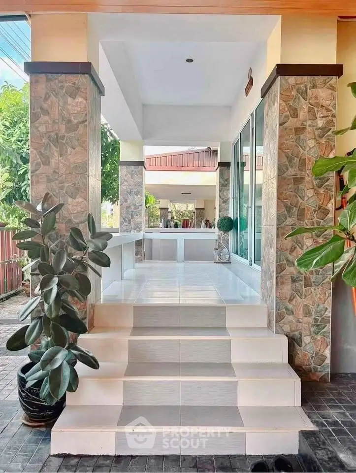 Charming entrance with tiled steps and lush greenery in a modern home exterior.
