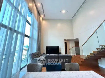 Luxurious high-ceiling living room with modern furniture and large windows.