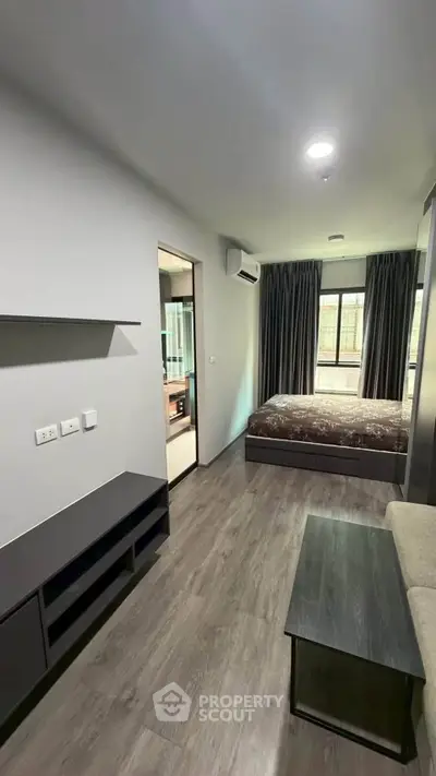 Modern studio apartment with sleek furnishings and large window for natural light.