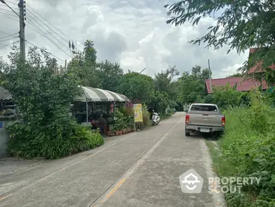 Charming suburban street with lush greenery and parked vehicles, ideal for tranquil living.