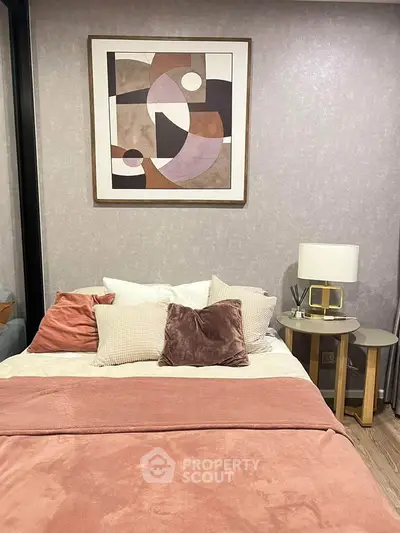 Cozy bedroom with modern decor and abstract art, featuring plush pillows and soft lighting for a relaxing ambiance.