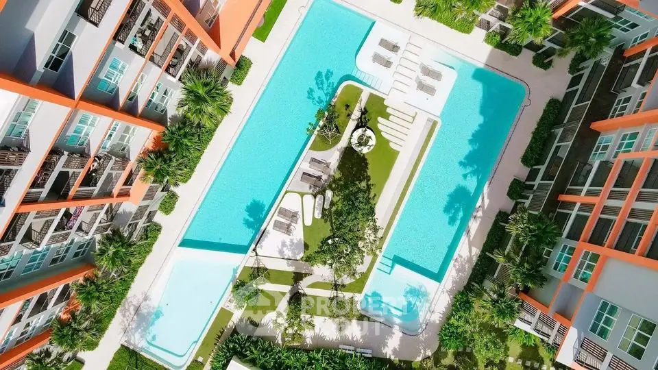 Stunning aerial view of modern apartment complex with large swimming pool and lush greenery.