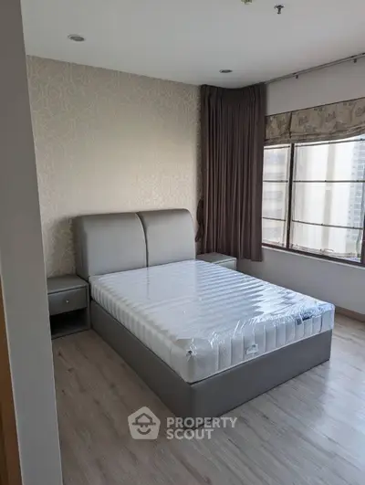 Modern bedroom with large window and stylish decor in a high-rise apartment.