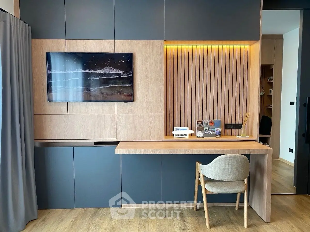 Modern study area with sleek wooden desk and wall-mounted TV in stylish apartment.