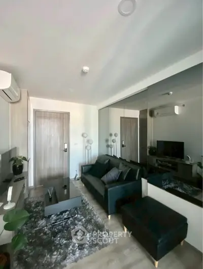 Modern living room with sleek furniture and mirrored wall enhancing space.