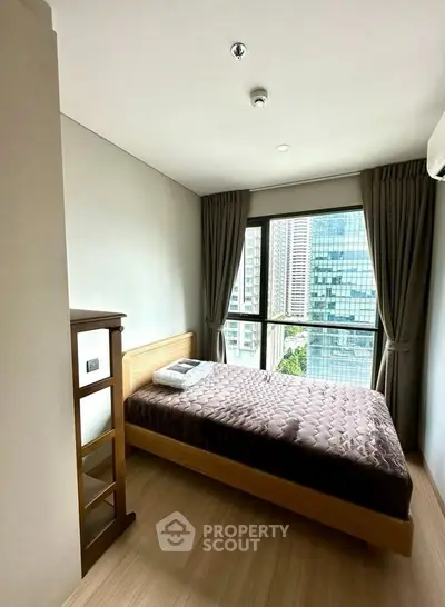 Modern bedroom with city view, featuring a cozy bed and large window with curtains.