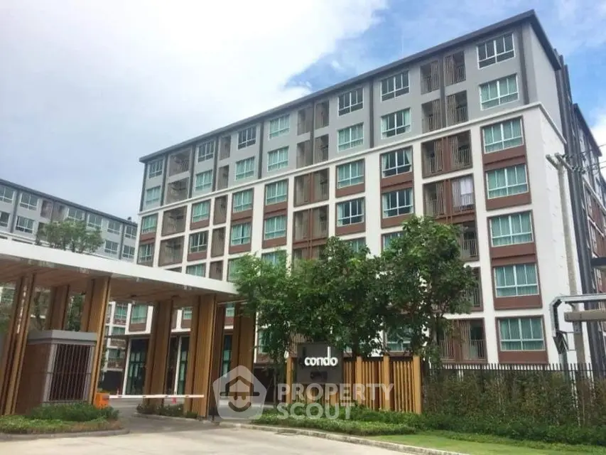 Modern condominium building with lush greenery and clear sky view.
